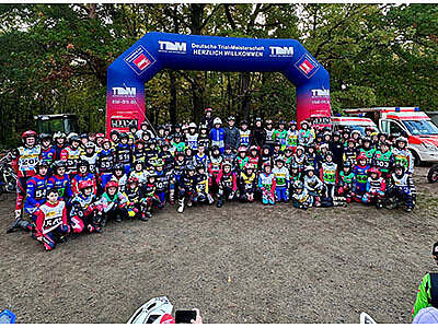 Gruppenfoto der Teilnehmer der Deutschen Trial-Meisterschaft unter einem Startbogen.